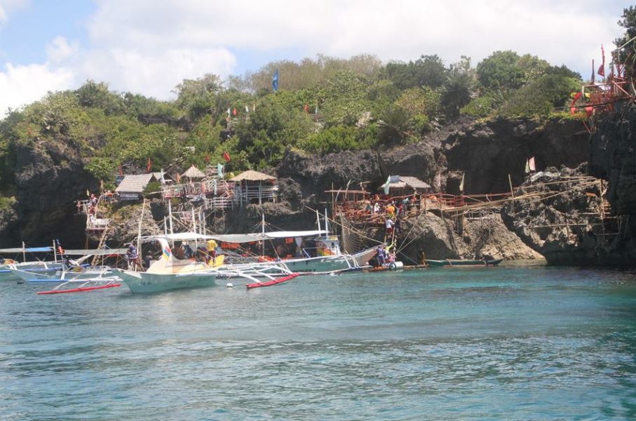 Traditional Filipino outrigger boats docked at Carabao Island cliff-side restaurants and dive platforms near Boracay Philippines