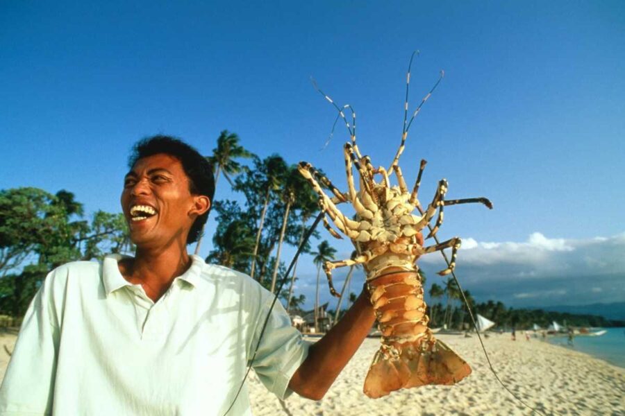 A local holding a fresh crayfish on the beach at Boracay