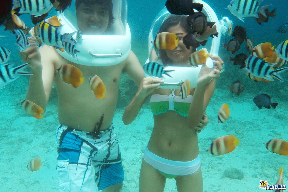 Two people feeding fish while helmet diving in Boracay